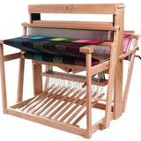 4 shaft weaving loom made from hard wood beech. The loom has a colourful length of fabric on it. 